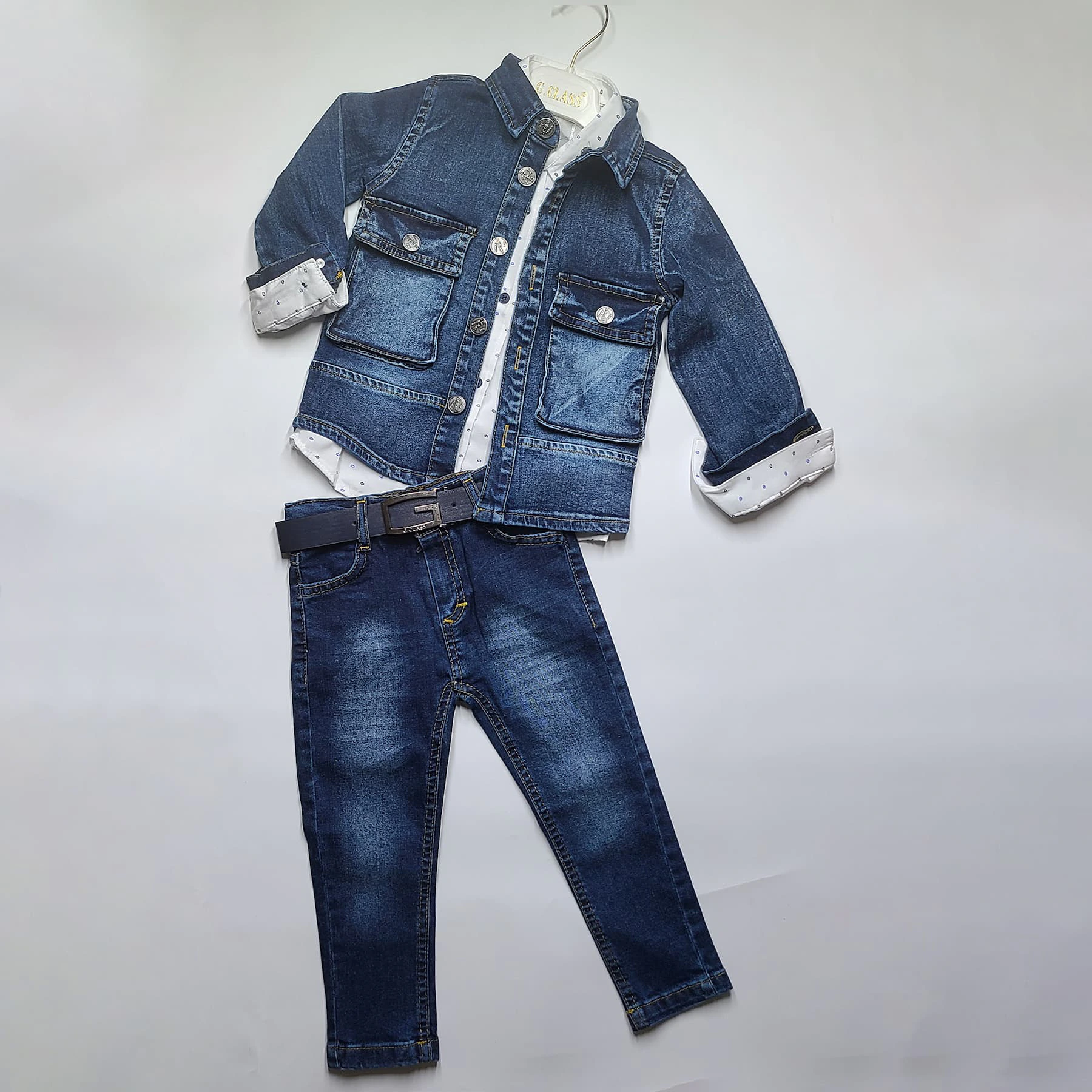 Le 2208-Ensemble bébé comprend une veste en jean, une chemise blanche à pois, un jean bleu et une ceinture foncée, soigneusement présentés sur un cintre blanc sur un fond blanc uni.