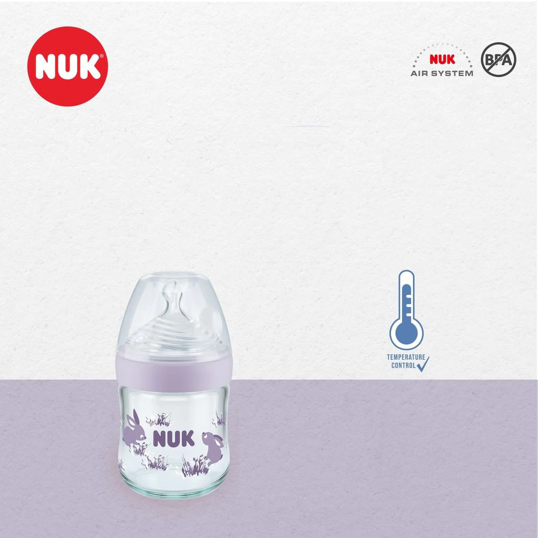 biberon-nuk-verre-120ml Un biberon NUK 028-Biberon en verre NATURE SENSE 120ml 0-6m avec un bouchon transparent et un motif d'animal violet est représenté sur un fond violet clair et blanc, avec les logos NUK, Air System, sans BPA, et Temperature Control.