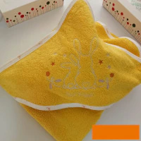 La 14056-Sortie de bain est une serviette jaune avec des bordures blanches, représentant un contour brodé de deux lapins - un grand, un petit - entourés d'étoiles et de fleurs. Elle est soigneusement pliée sur une surface blanche, avec des boîtes à motifs à proximité.